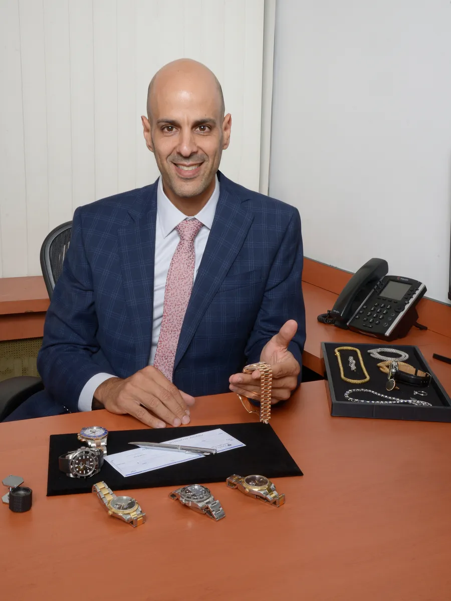 Steven Madar, GoldVara founder, at his desk with a tray of jewelry and watches